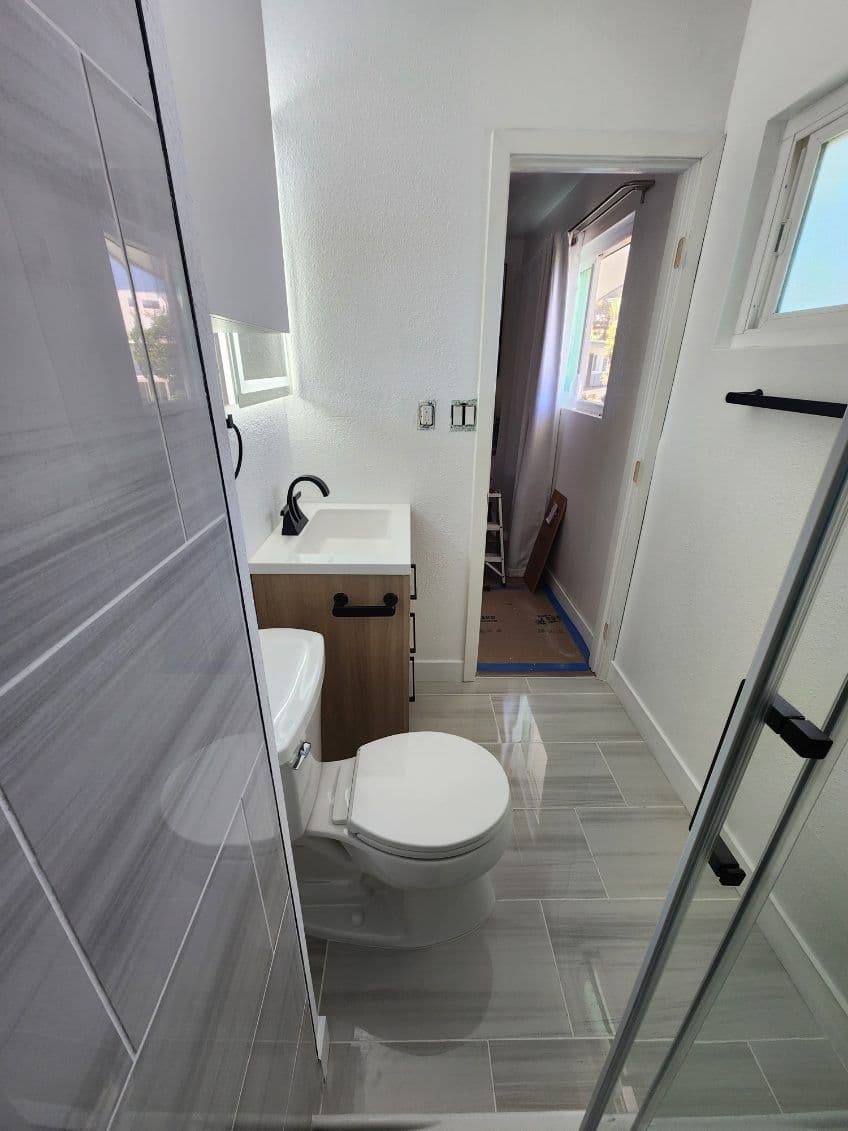 Modern bathroom interior featuring a shower, sink, and toilet with sleek design.