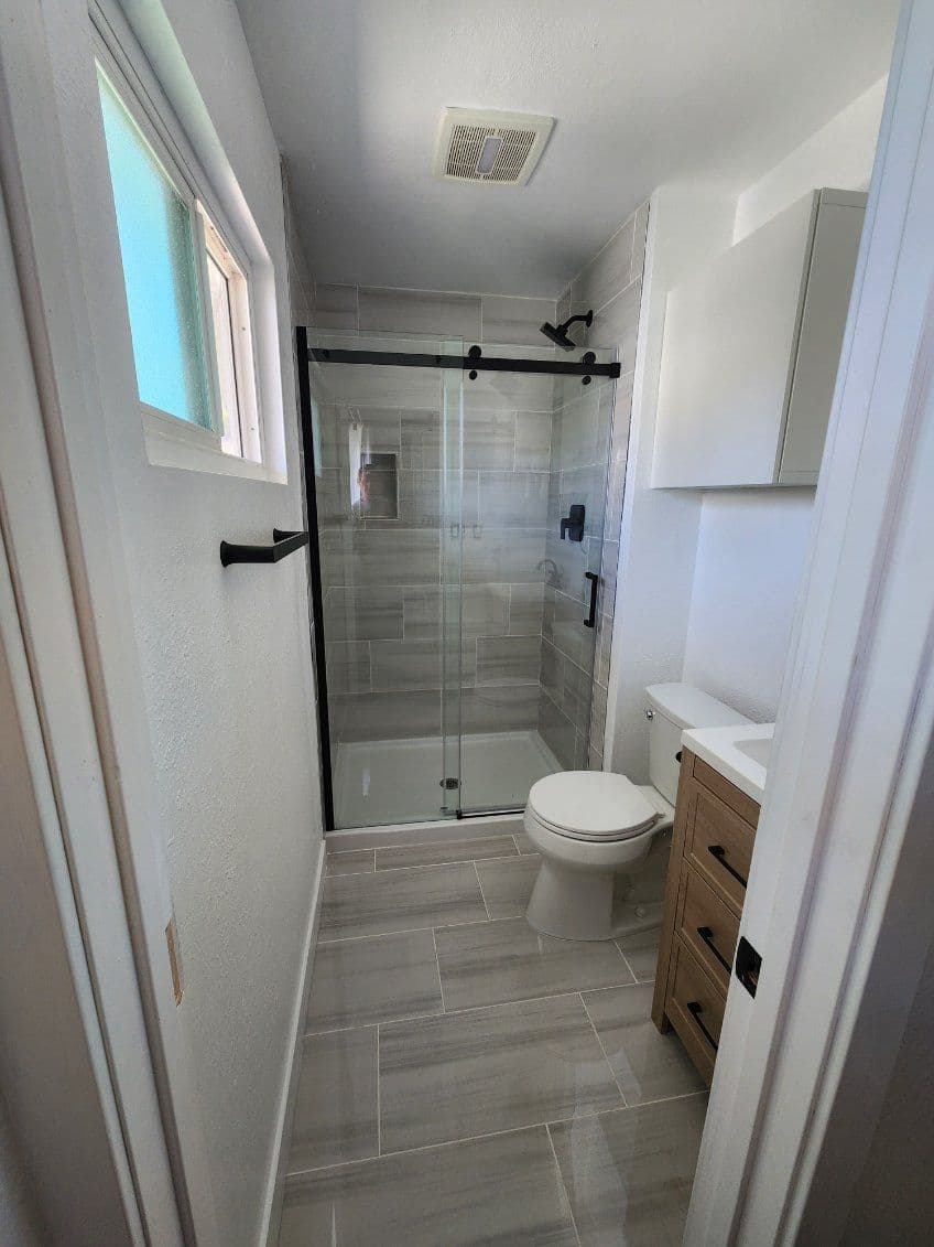 Modern bathroom design featuring a glass shower, vanity, and neutral tile flooring.